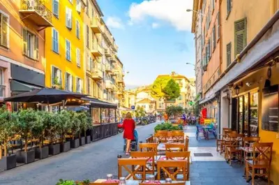 a woman walking down a street with tables and chairs at Beautiful 4 rooms sea airport in Nice