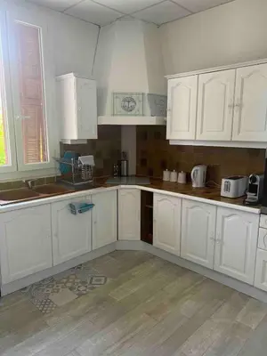 an empty kitchen with white cabinets at Appartement spacieux proche mer idéalement situé in Cagnes-sur-Mer