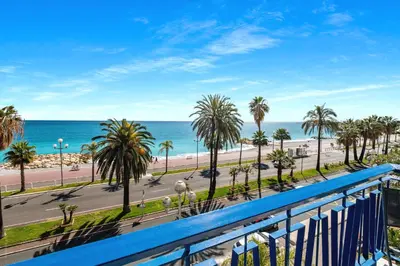 a balcony with a view of the beach and palm trees at Amazing Sunset in Nice
