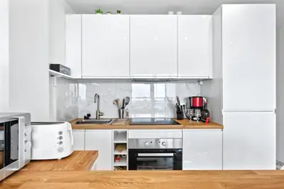 a white kitchen with white cabinets and a sink at Amazing Sunset in Nice