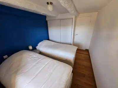 two beds in a small room with a blue wall at Plaisirs entre mer et montagne in Aspremont