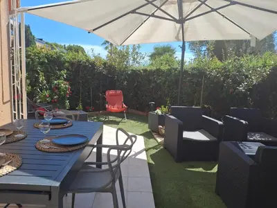 a patio with a blue table and chairs and an umbrella at Lovely apartment with private garden and a swimming-pool in Nice