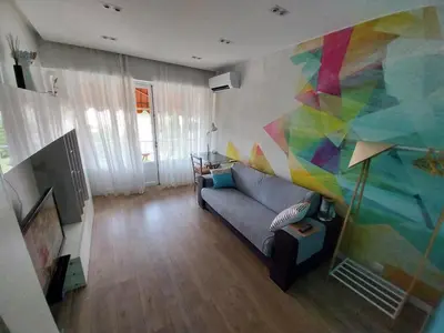 a living room with a couch and a colorful wall at Modern Appart Nice, proche Gare Riquier in Nice