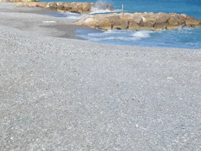 a sandy beach with rocks in the water at Apartment Villa HenriIV in Nice