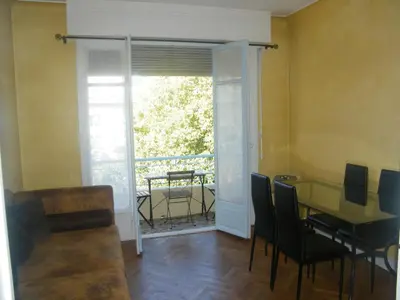 a dining room with a table and chairs and a balcony at Apartment Villa HenriIV in Nice