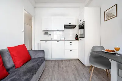 a living room with a couch and a kitchen at Appartement Perle - Welkeys in Nice