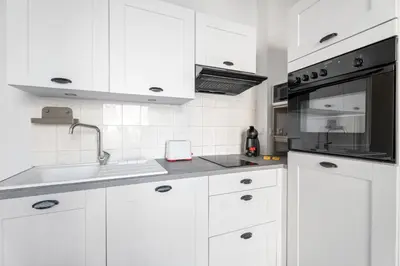 a white kitchen with a sink and a microwave at Appartement Perle - Welkeys in Nice