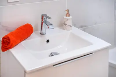 a white bathroom sink with an orange towel on it at Azur Stay 3 Start Beach 8 min Tram Airport 5m in Nice