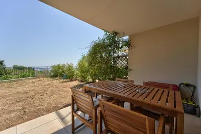 a wooden table and chairs on a patio at Lovely 1BR with garden, private parking & Sea View in Nice