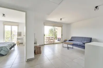 a white bedroom with a blue couch and a living room at Lovely 1BR with garden, private parking & Sea View in Nice