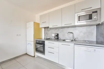 a kitchen with white cabinets and a sink and a refrigerator at Lovely 1BR with garden, private parking & Sea View in Nice