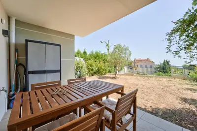 a wooden table and chairs on a patio at Lovely 1BR with garden, private parking & Sea View in Nice