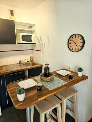 a kitchen with a table and a clock on the wall at Charming studio in Nice