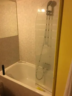a bathroom with a tub with a glass shower door at Teranga in Nice