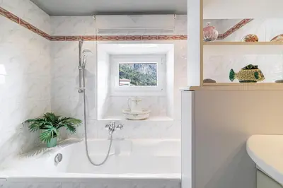 a white bathroom with a tub and a sink at La Terrasse de Bracco in Beaulieu-sur-Mer