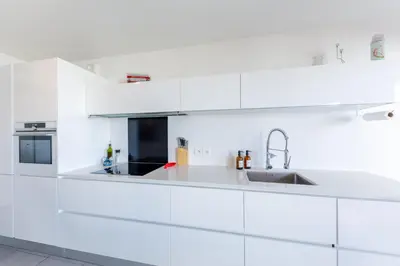 a white kitchen with white cabinets and a sink at Green Hill Appartement à Nice Terrasse 130m2, Vue panoramique, Piscine, Parking Privé, Climatisation, WiFi in Nice