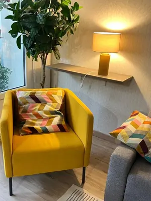 a yellow chair with a pillow in a living room at Bel appartement spacieux avec joli balcon arboré, calme, bien situé, centre ville in Nice