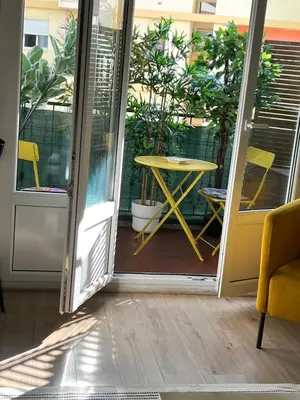 a glass door leading to a patio with a yellow table at Bel appartement spacieux avec joli balcon arboré, calme, bien situé, centre ville in Nice