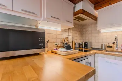 a kitchen with white cabinets and a black microwave at Antibes Centre 2 pièces cosy proche remparts in Nice