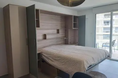 a bedroom with a bed and a wooden wall at Seafront apartment with pool and comfort in Saint-Laurent-du-Var