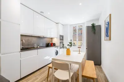 a kitchen with white cabinets and a table and chairs at Nice Renting - REPUBLIQUE - Garibaldi Chic 3 Bedrooms 3 Bathrooms Balcony AirCon in Nice