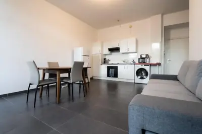 a living room with a couch and a table and a kitchen at Le Malausséna in Nice