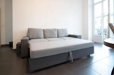 a large bed in a room with a large window at Le Malausséna in Nice