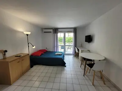 a bedroom with a bed and a table and a desk at Studio climatisation balcon à 5 min de la plage in Nice