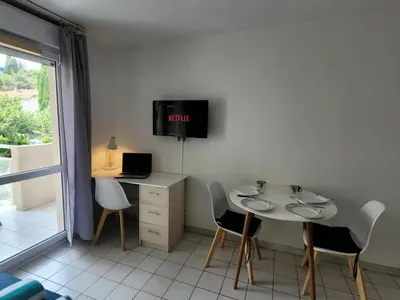 a room with a table and chairs and a tv at Studio climatisation balcon à 5 min de la plage in Nice