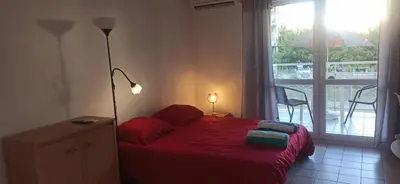 a bedroom with a red bed and a balcony at Studio climatisation balcon à 5 min de la plage in Nice