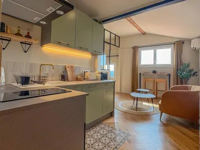 a kitchen with green cabinets and a living room at Charmant 2 pièces rénové avec vue mer in Villefranche-sur-Mer