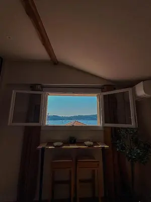 a window in a room with a table and two stools at Charmant 2 pièces rénové avec vue mer in Villefranche-sur-Mer