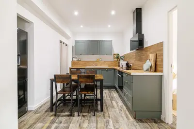 a kitchen with green cabinets and a table and chairs at Ultra Central Rue Massena 1 Bdr in Nice