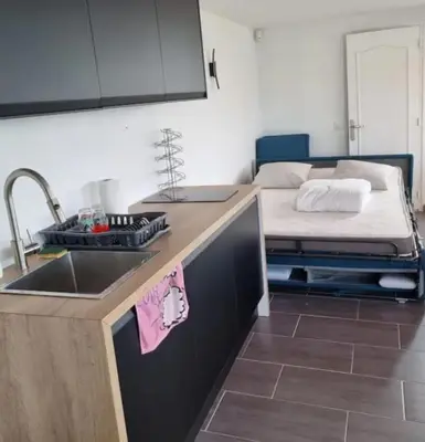 a kitchen with a sink and a bed in the background at Logement vue mer - Nice ouest in Nice