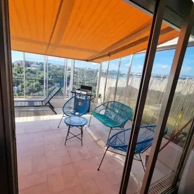 a screened in porch with chairs and a grill at Logement vue mer - Nice ouest in Nice