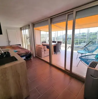 a bedroom with a bed and a balcony with a table at Logement vue mer - Nice ouest in Nice