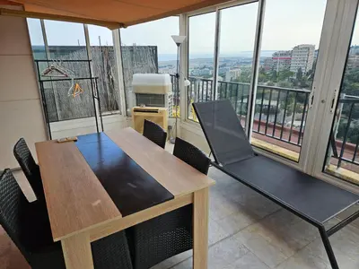 a dining table and chairs in a room with windows at Logement vue mer - Nice ouest in Nice