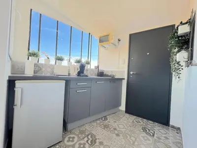 a kitchen with a refrigerator and a counter with windows at ⁂ Cocon ensoleillé proche de la plage in Nice
