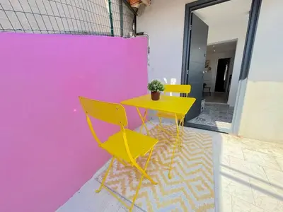 a yellow table and chairs next to a pink wall at ⁂ Cocon ensoleillé proche de la plage in Nice