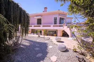 a large pink house with trees in front of it at Villa le Mazet, Nice, piscine, vue mer, Promenade des Anglais, Baie des Anges in Nice