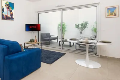 a living room with a blue couch and a table at Appartement neuf - Patio intérieur - Parking - EF in Èze