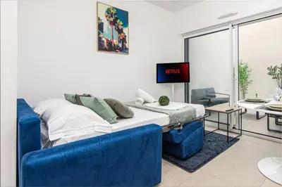 a room with a bed with blue chairs and a tv at Appartement neuf - Patio intérieur - Parking - EF in Èze