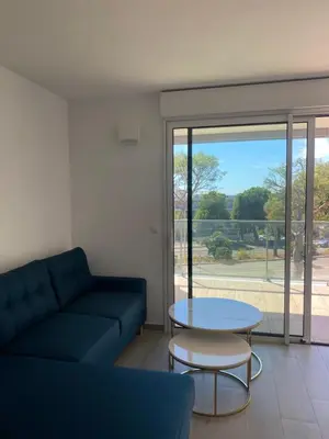 a living room with a couch and a table at New flat with swimming pool on rooftop in Saint-Laurent-du-Var