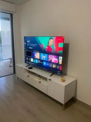 a flat screen tv sitting on a stand in a living room at New flat with swimming pool on rooftop in Saint-Laurent-du-Var