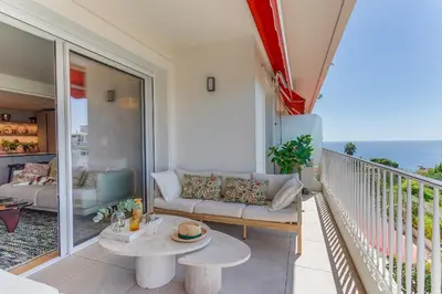 a living room with a couch and a table on a balcony at MONT BORON PALMS AP4480 by Riviera Holiday Homes in Nice