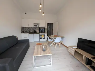 a living room with a black couch and a table at Bel appartement proche centre 15 minutes in Nice