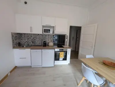 a kitchen with white cabinets and a wooden table at Bel appartement proche centre 15 minutes in Nice