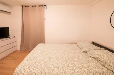 a white bedroom with a bed and a television at Studio Place Masséna in Nice
