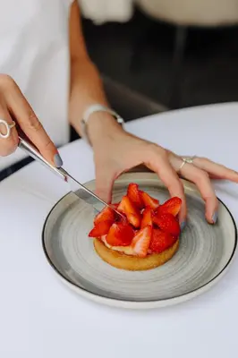 a person cutting a plate with strawberries on it at Hôtel & Appartements Monsigny in Nice