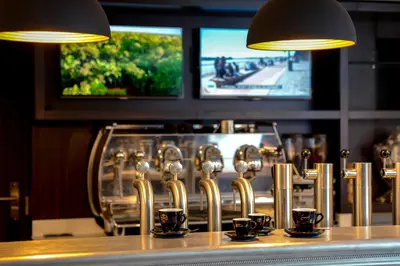 a bar with a row of silver chairs and cups at Hôtel & Appartements Monsigny in Nice